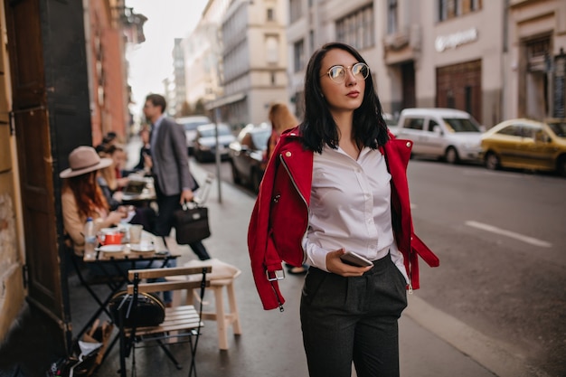 Fashionable brunette woman in office attire spending time, walking around city