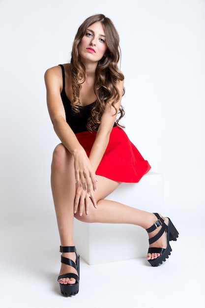 Fashionable brunette woman with long slim legs posing in studio.