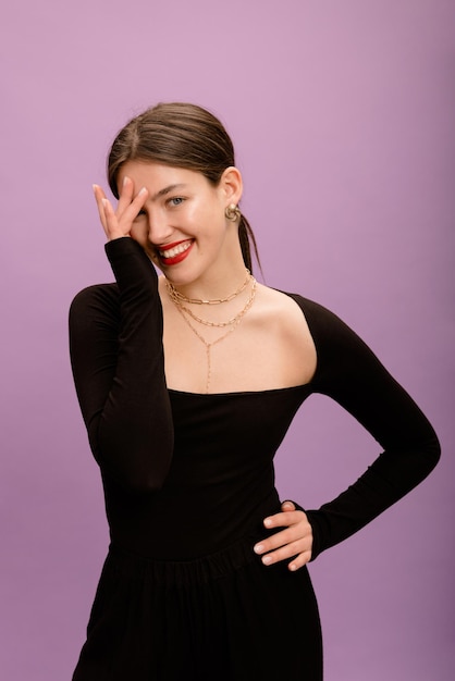 Fashionable caucasian brunette girl with collected hair and red lips wears black blouse on purple background Elegant style concept