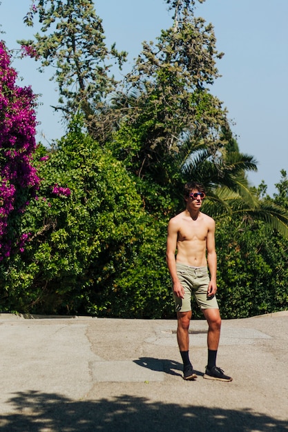 Fashionable charming young man with shoes and swimming goggles standing in park