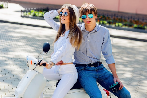 Free photo fashionable couple posing on the street, siting on scooter