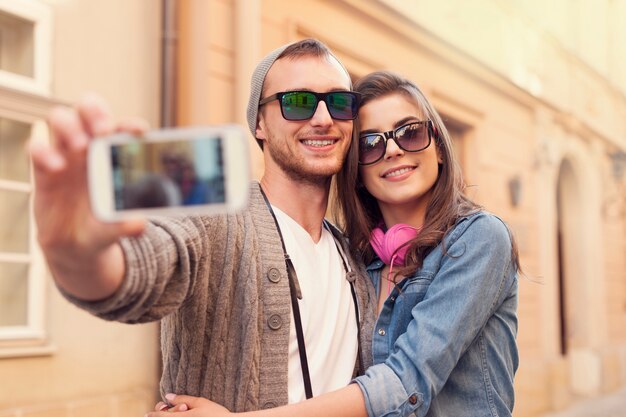 Fashionable couple taking selfie by mobile phone