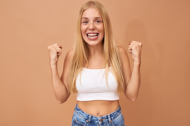 Fashionable cute teenage girl with blonde hair wears jeans and white top