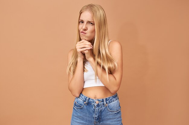 Fashionable cute teenage girl with blonde hair wears jeans and white top