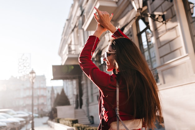 Fashionable european woman with long dark hair exploring town in sunny day