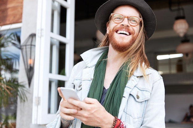 Fashionable hipster guy dressed in stylish black hat and denim shirt