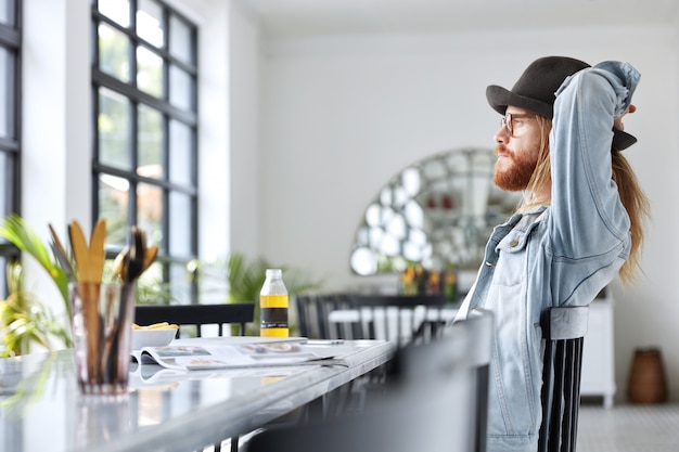 Fashionable hipster guy dressed in stylish black hat and denim shirt