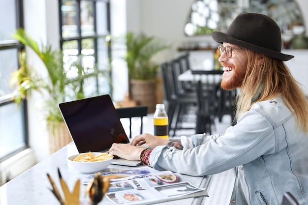 Fashionable hipster guy dressed in stylish black hat and denim shirt