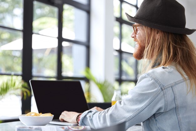 Fashionable hipster guy dressed in stylish black hat and denim shirt