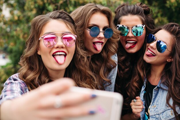 Fashionable ladies with hairstyle taking selfie outdoors.