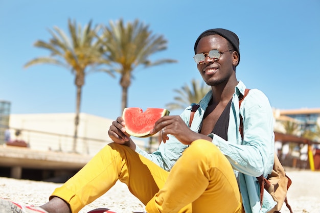 Free photo fashionable male student eating ripe watermelon