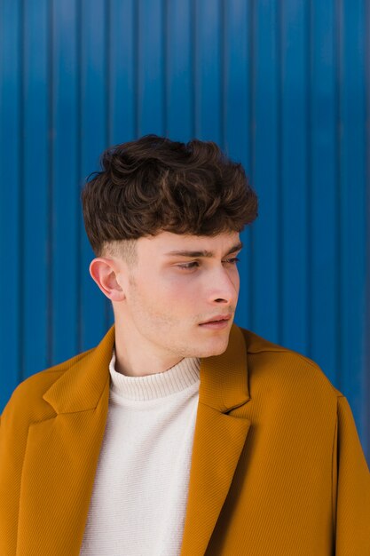 Fashionable man in front of blue wall