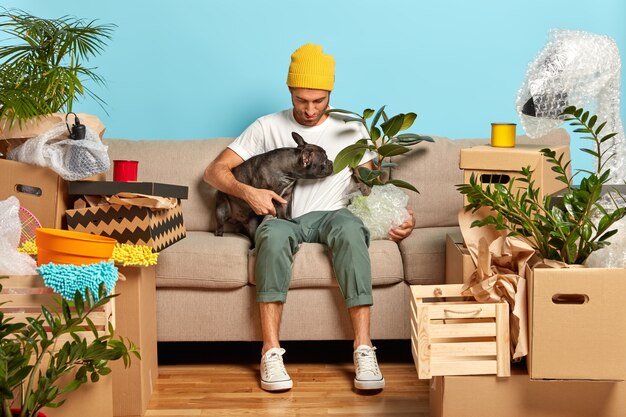 Fashionable man poses on cozy sofa with favourite pet