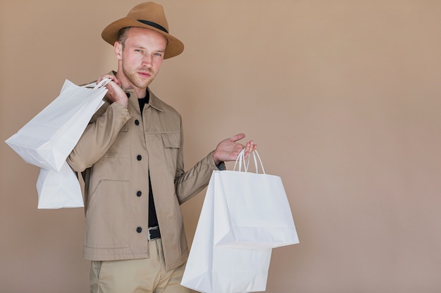 カメラを探している買い物袋を持つファッショナブルな男