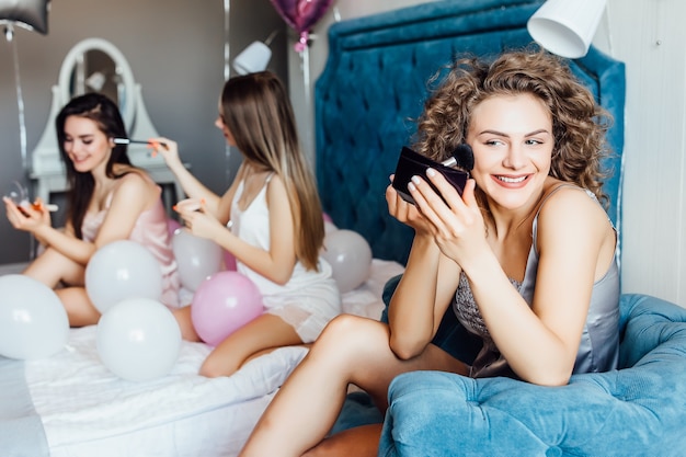 Fashionable models enjoying meeting indoor, helping with make up