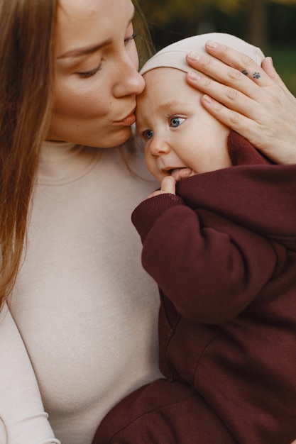 Fashionable mother with daughter. People walks outside. Woman in a brown sweater.