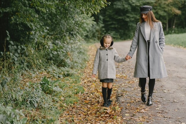 Fashionable mother with daughter. People walks outside. Woman in a gray coat.