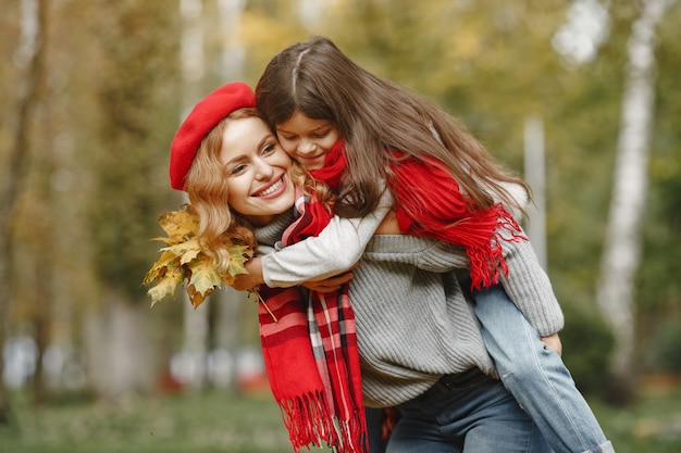 Fashionable mother with daughter. Yellow autumn. Woman in a red scarf.