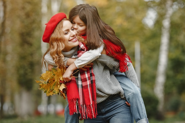 Fashionable mother with daughter. Yellow autumn. Woman in a red scarf.