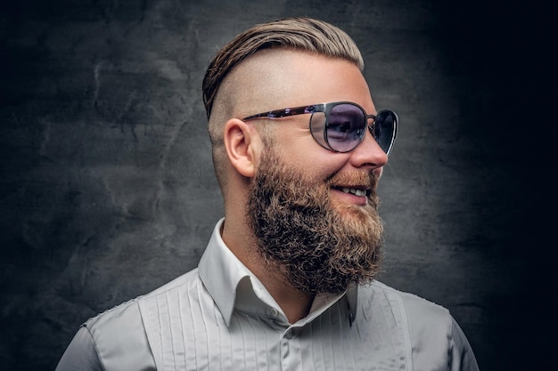 Модный портрет бородатого мужчины в фиолетовых солнцезащитных очках на сером фоне виньетки.