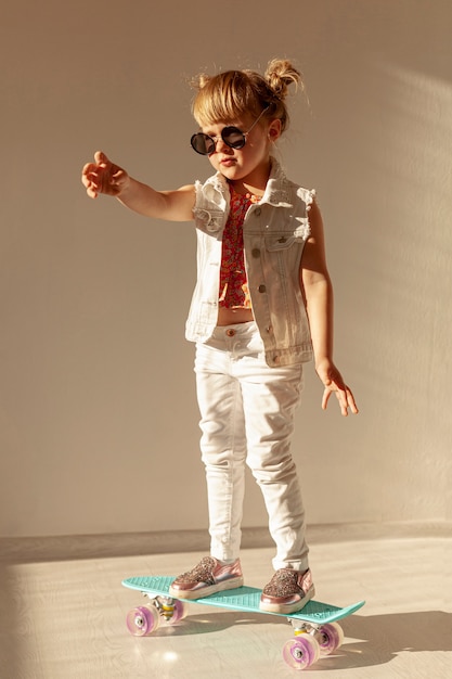 Fashionable toddler on skateboard full shot