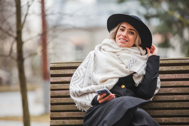 Foto gratuita donna alla moda su una panchina in una giornata di pioggia