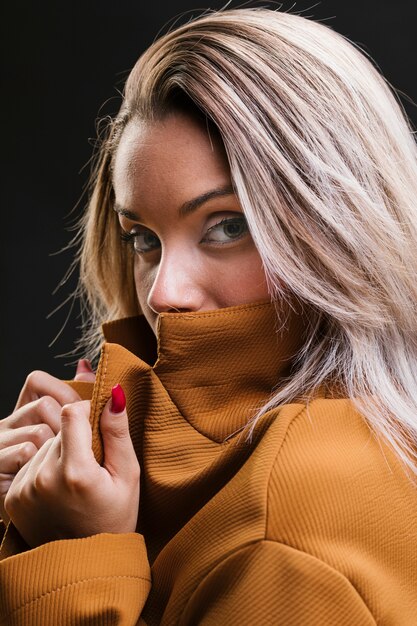 Fashionable woman covering her mouth with yellow jacket