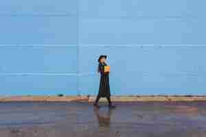 Free photo fashionable woman in front of blue wall