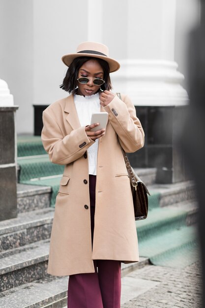 fashionable woman looking on her phone outside