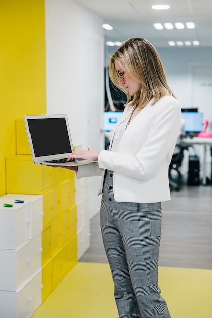 Fashionable woman in office using laptop