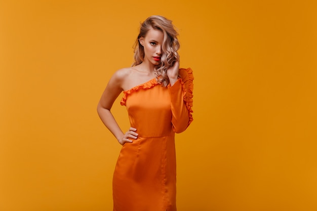 Fashionable woman in orange dress looking to the front