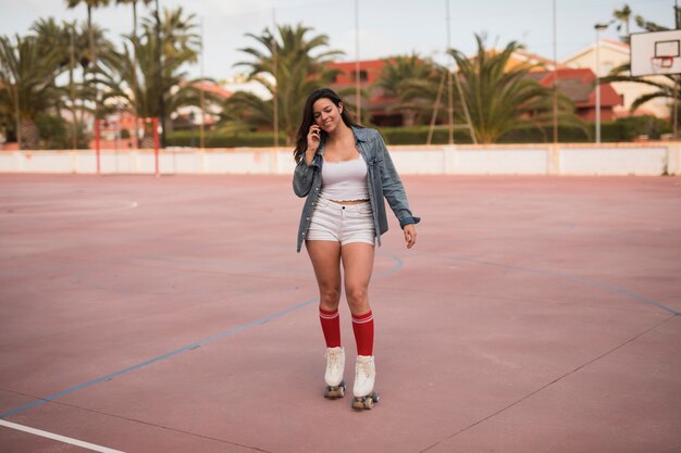 Fashionable young female skater talking on mobile phone