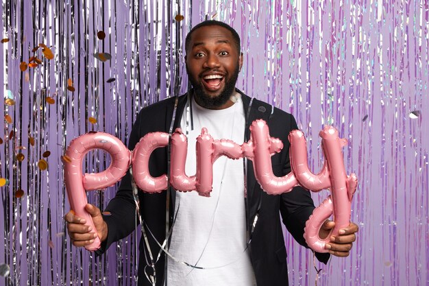 Fashionable young man holding party balloons