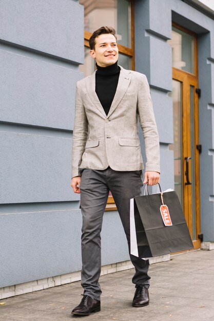 Fashionable young man holding shopping bag with sale tag