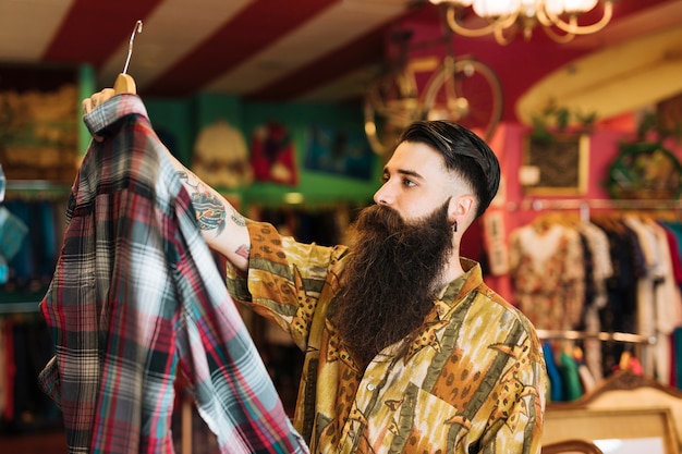 Модный молодой человек покупает одежду в магазине