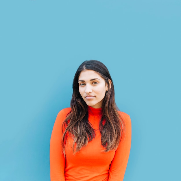 Fashionable young woman standing in front of blue backdrop