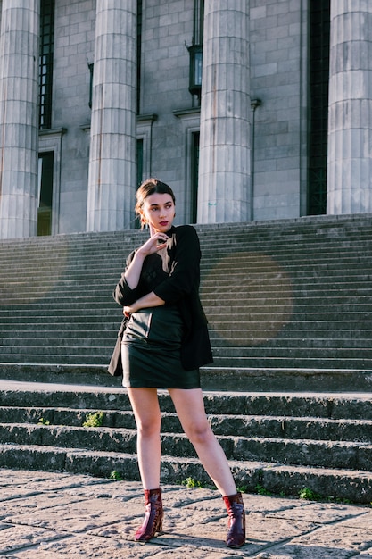 Free photo fashionable young woman standing in front of staircase