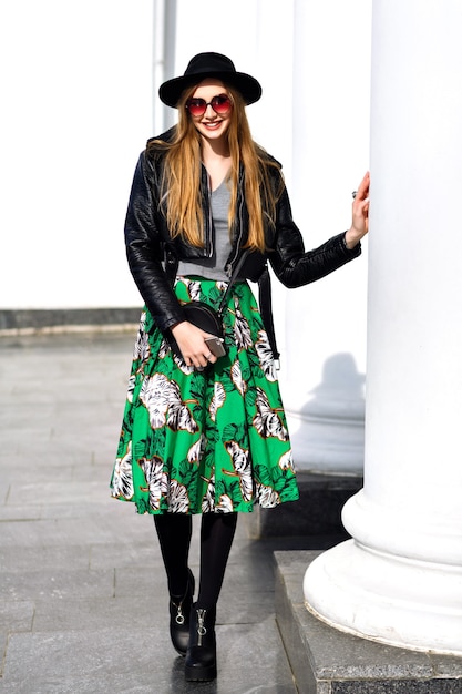 Free photo fashionable young woman walking on the street with leather jacket and floral skirt