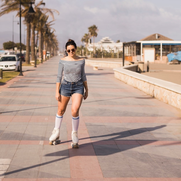 ファッショナブルな若い女性が身に着けているローラースケートスケート街の歩道