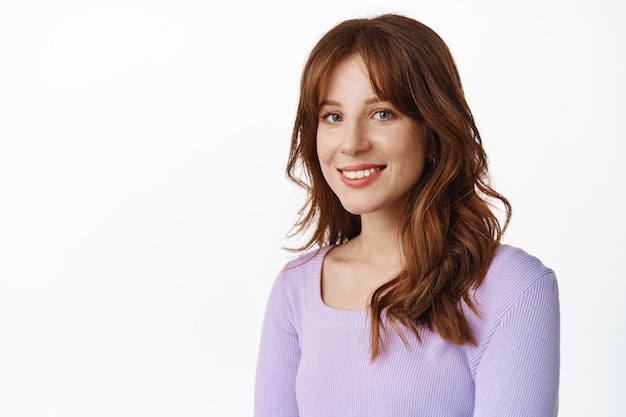 fashionable young woman with freckles and white smile, standing in purple blouse with relaxed happy face expression