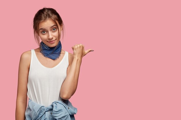 Fashionable young woman with glasses posing against the pink wall