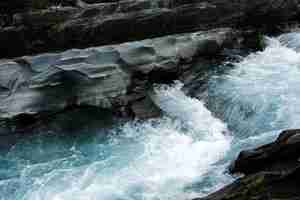 Free photo fast flowing stream surrounded by cliffs and rocks at daylight