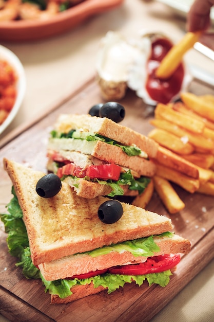 Fast food board with club sandwiches and french fries.