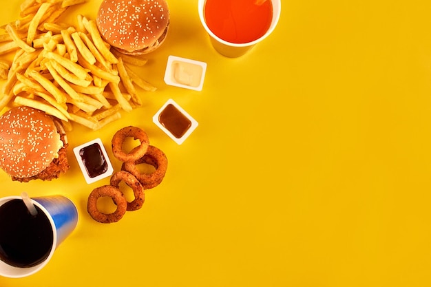 無料写真 脂っこい揚げ物レストランのファーストフードのコンセプトは、タマネギのリング、ハンバーガー、フライドチキン、フライドポテトをダイエットの誘惑の象徴として取り入れ、不健康な栄養をもたらします。