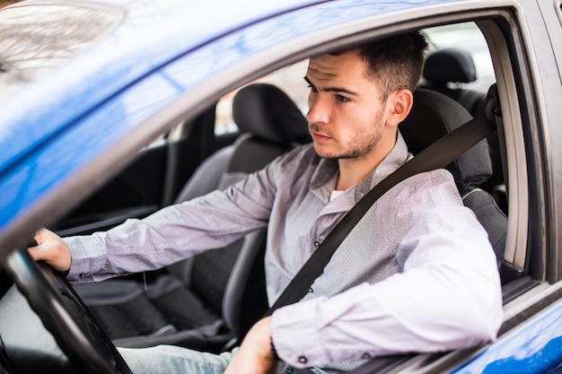 カーシートベルトを締めます。運転中の若い男の安全ベルトの安全性