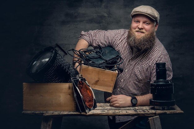 The fat bearded hipster male holds vintage 8 mm video camera and colorful soffits lamps.