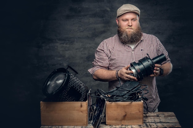 Foto gratuita il grasso hipster barbuto tiene in mano una videocamera vintage da 8 mm e lampade colorate per intradossi.