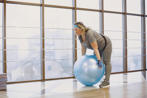 Толстая женщина на диете, фитнес. Портрет тучной женщины, тренирующейся в тренажерном зале.