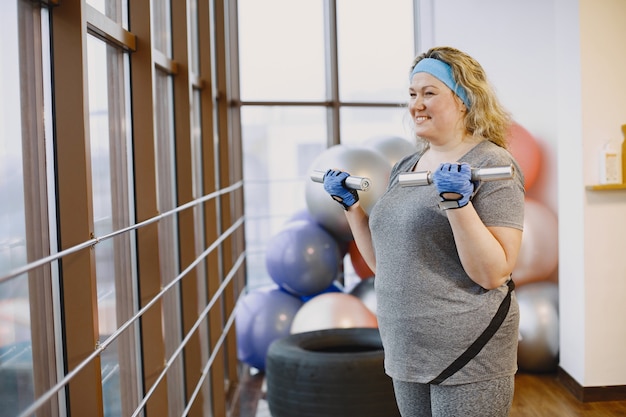 太った女性のダイエット、フィットネス。ジムで運動している肥満女性の肖像画。