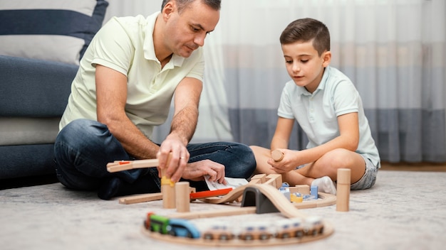 Бесплатное фото Отец и ребенок играют с игрушками в спальне